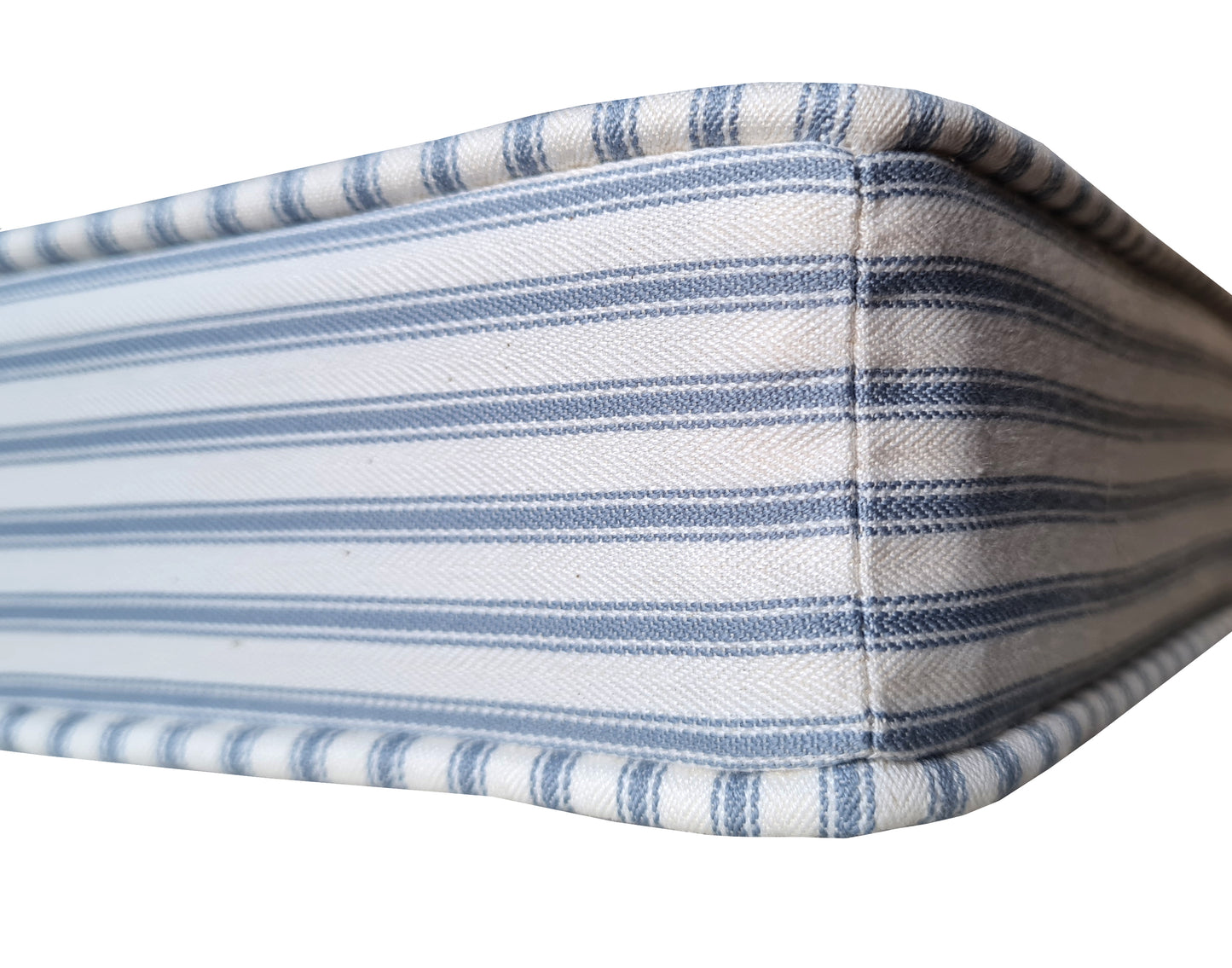 A close up of a high quality, luxury made to measure bench cushion with a firm foam inner with a stockinette wrap. The bench cushion cover is made with a UK made 100% cotton ticking fabric in a light blue and white natural coloured fabric. The custom made bench cushion has piping at the edges of the cushion in the same blue and white striped traditional french style ticking fabric. The natural cotton fabric bench cushion cover has a zip at the back so it can be removed for washing.
