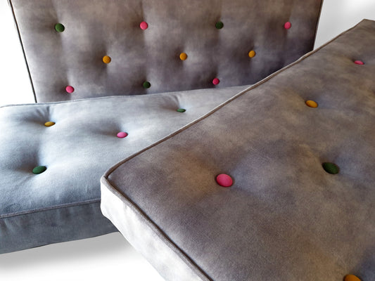 High quality velvet bench cushions in a light grey colour upholstery velour fabric with a slight mottled, semi plain pattern. The thick firm foam seating cushions have dacron on the foam and stockinette wrap. The comfortable and supportive dining banquette seat cushions are button tufted by hand with multicoloured buttons. Perfect for dinette seating. Wipe clean and stain resistant covers. Kept in place with velcro strips, ties which can be hung from a mounted rod or anti slip cloth.
