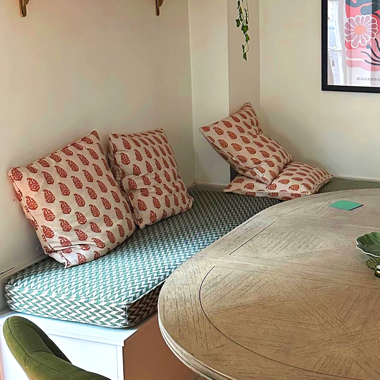 An in built corner seating area for a dining room space. Green and beige chevron geometric shape upholstery fabric which is stain resistant and hard wearing makes up the bench cushion cover, on top of dacron and firm foam filling. The made to measure L shaped bench cushions are hand made in the UK with high quality, long lasting materials, to a very high standard. Built in kitchen seating cushions bespoke with green and natural coloured fabric. Zip at the back of the bench cushion cover, piping.