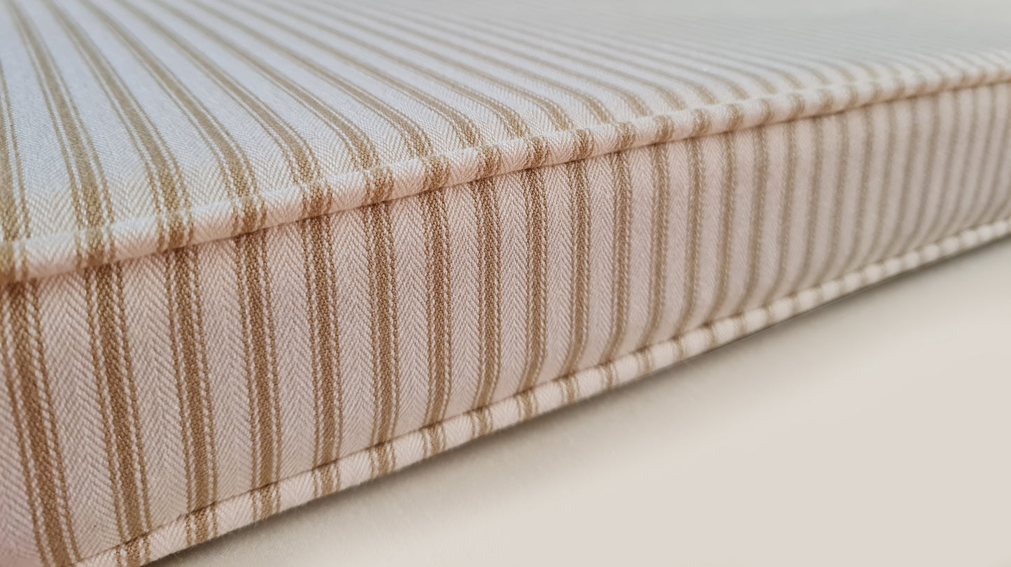 100% cotton ticking fabric bench cushion cover in off white and beige stripes. Made to measure bench cushion with firm seating foam and dacron wrap for comfortable seat cushions. Bench cushion in french style ticking fabric. Striped bench cushion in cream and neutral coloured stripe fabric. Made in the UK bench cushions with zippers, piping and button tufting. Hand made window seat cushions, any shape or size, cut outs, curves, odd shapes. Foam seat cushions made for church pew seats in stripes
