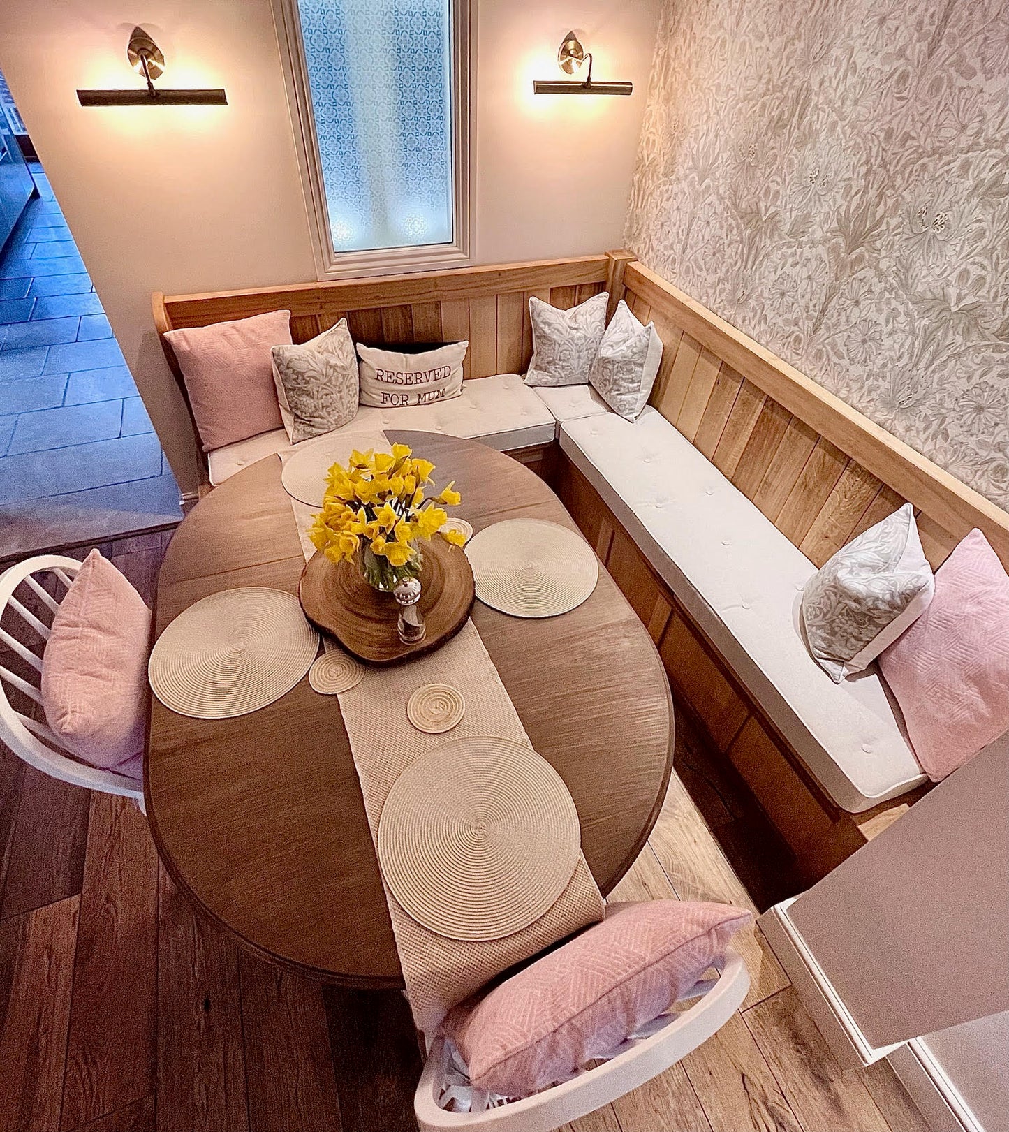 A kitchen dining banquette seating area with a set of made to measure foam bench cushions. The storage seating area is made up with light brown wood panelling and it has three piped and buttoned bench seating cushions on top made with an oatmeal, cream coloured fabric. The hardwearing twill fabric bench cushion cover has a stain resistant treatment making this box edged bench cushion perfect for use around kids, children and pets. Hardwearing and easy clean seat cushions for benches and seats.